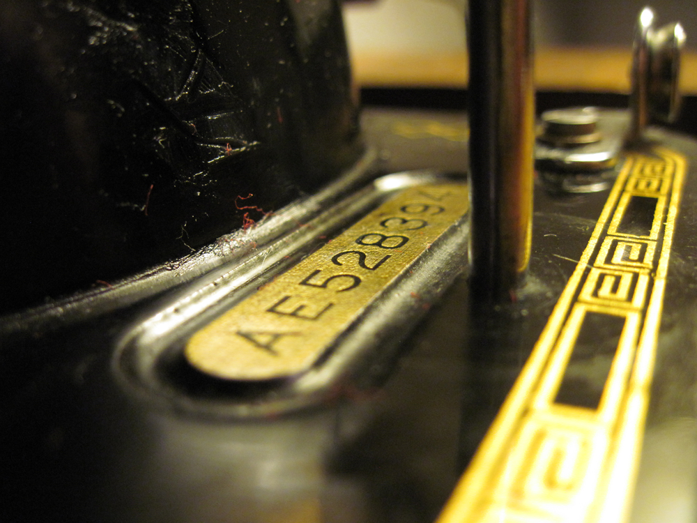 A closeup of the machine's serial number plate behind the front bobbin winder spool pin.