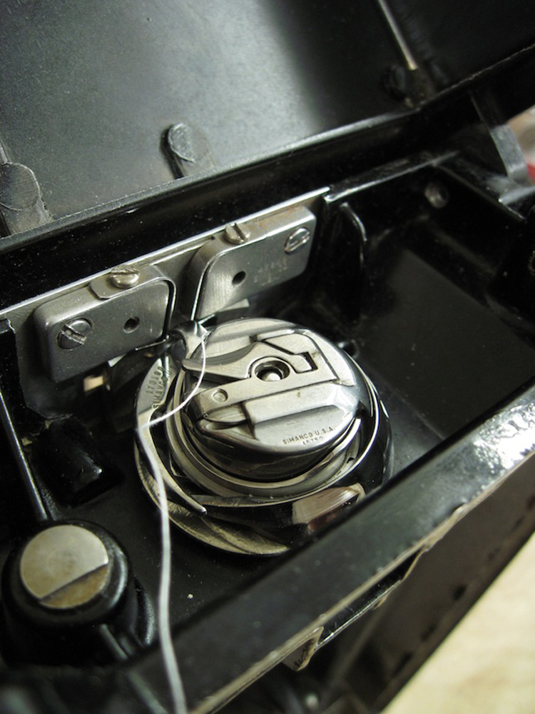 A closeup of the bobbin case in the hook.