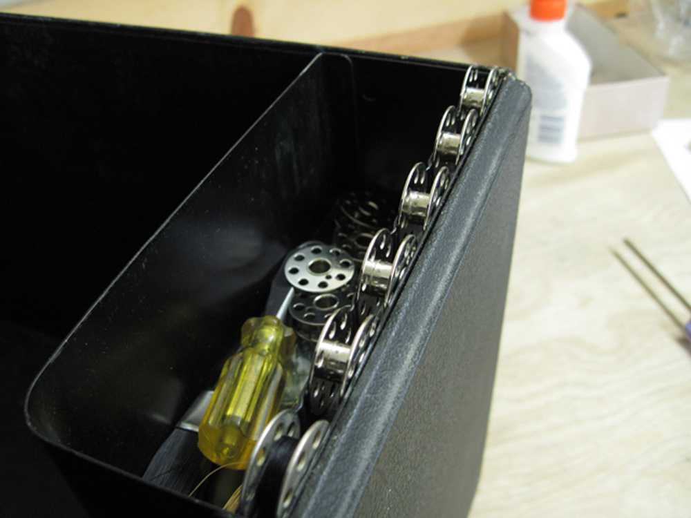 Empty bobbins in their holder within the case.
