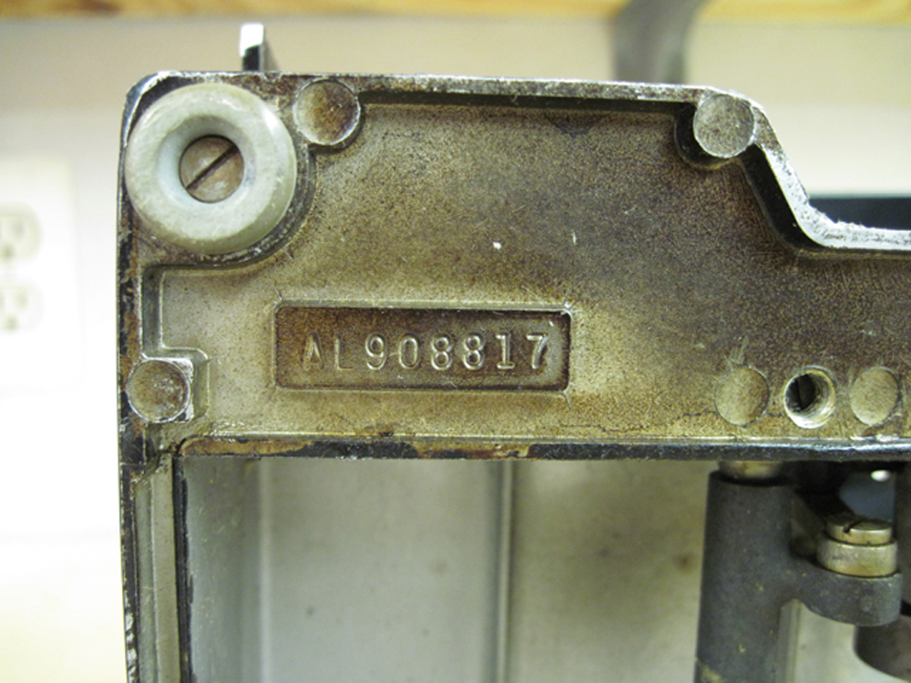 A closeup of the machine serial number on the bottom of the machine, AL908817.