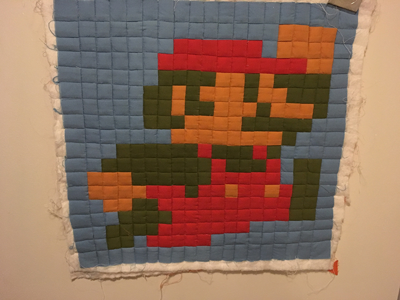 The smaller project with the quilting complete. Batting hangs out from around the unbound edges.