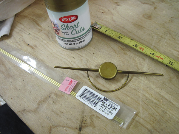 The broken dial pointer, a small can of Krylon Short Cuts gold paint, and some 1/16&″ round brass stock.